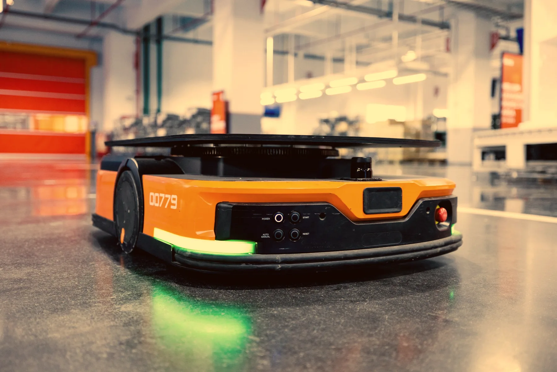 Orange autonom logistikrobot (AGV) på ett industrigolv